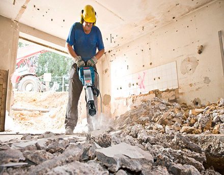 Operario ejecutando demolición controlada de losa con martillo neumático